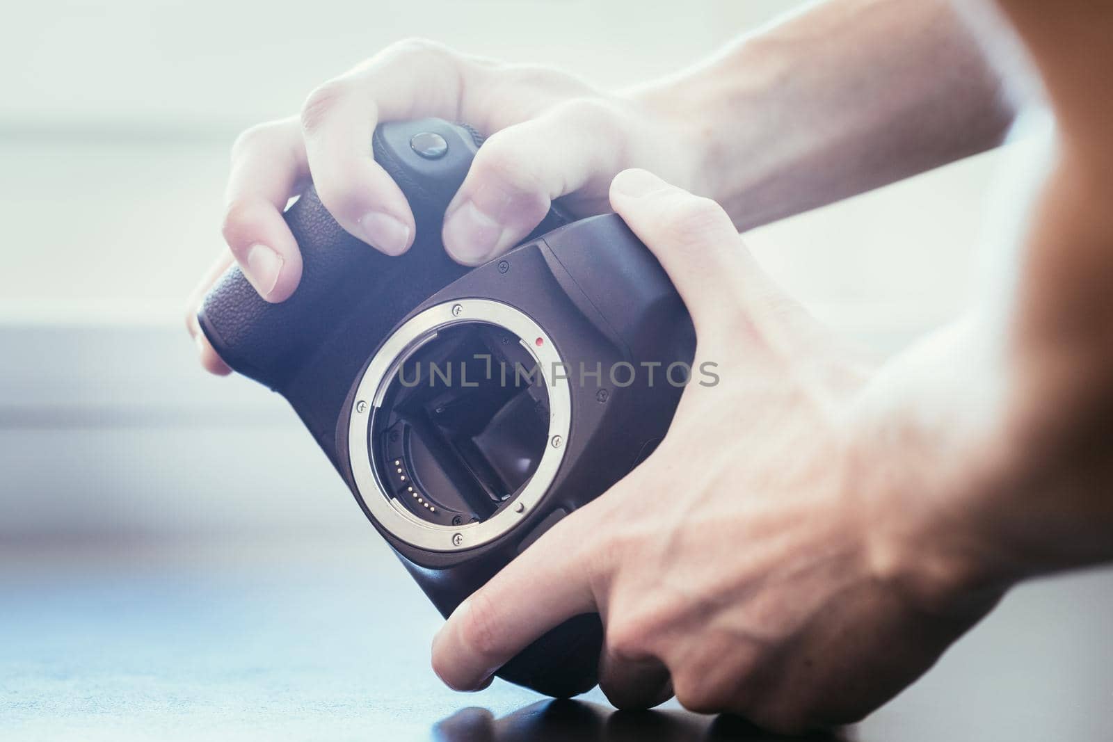 Hands of a photographer are touching a professional reflex camera, open sensor