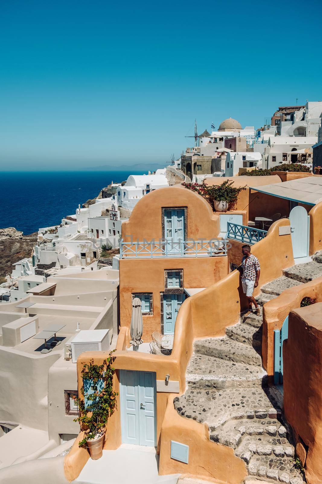 Santorini Greece, young man on luxury vacation at the Island of Santorini watching sunrise by the blue dome church and whitewashed village of Oia Santorini Greece during sunrise, men and woman on holiday in Greece by fokkebok