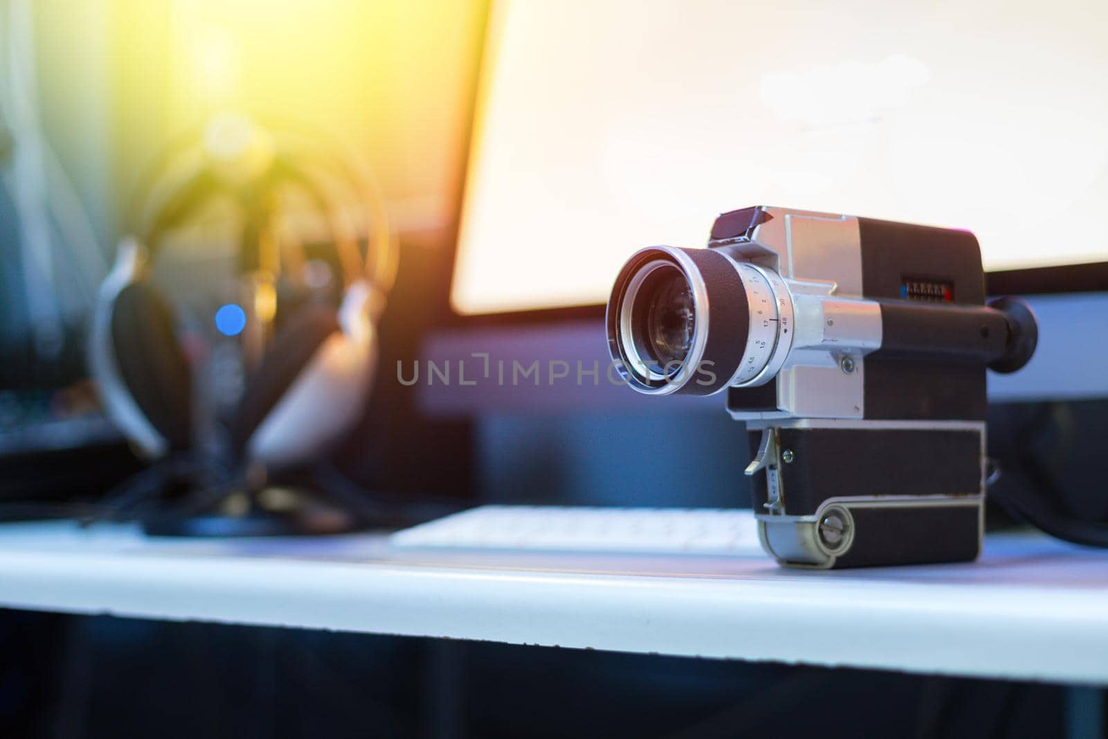 Vintage old movie camera, computer for cutting in the blurry background. Sunshine.