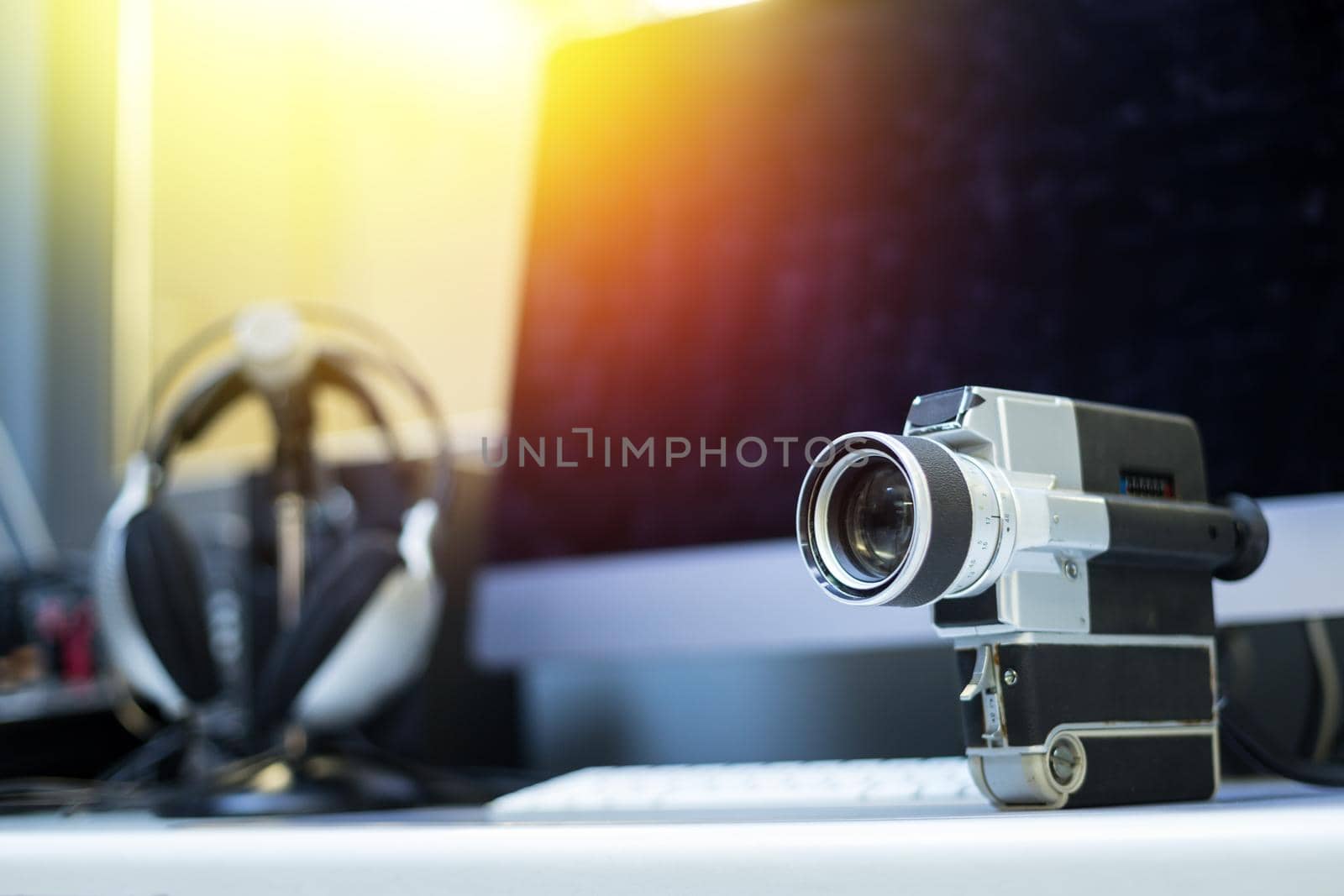 Vintage old movie camera, computer for cutting in the blurry background. Sunshine.