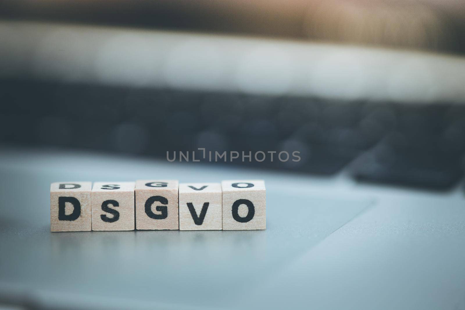 Wooden cubes with the letters “DGSVO” for Datenschutzgrundverordnung are lying on a laptop