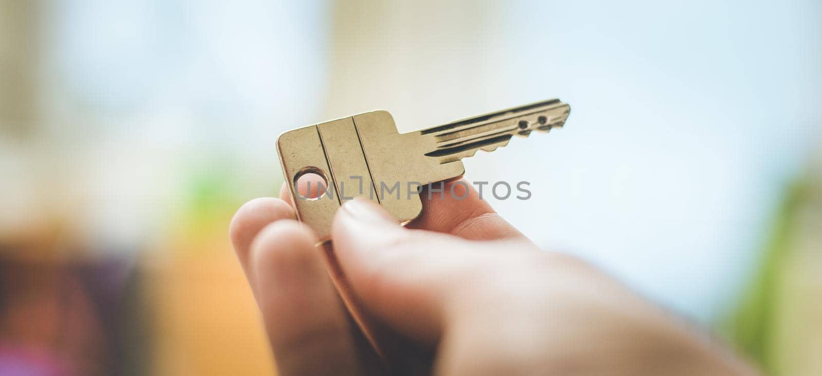 Moving into a new home: Close up of a hand holding a key. Property and real estate. by Daxenbichler