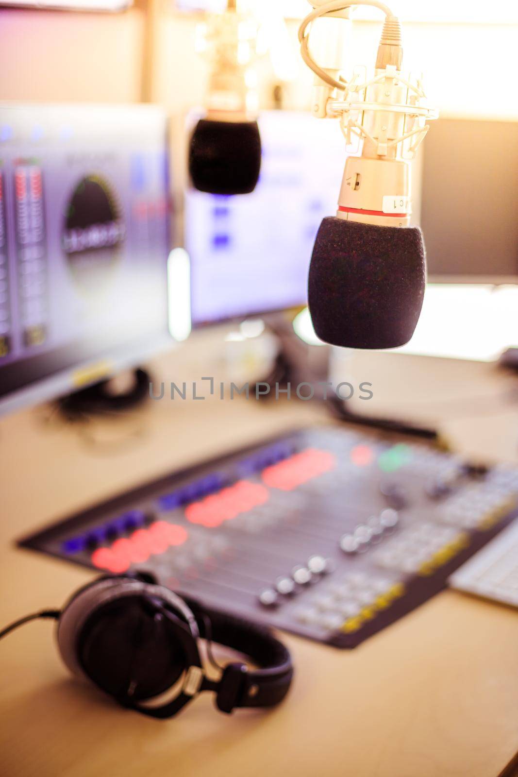 Radio broadcasting studio: Microphone in the foreground, modern studio in the blurry background by Daxenbichler