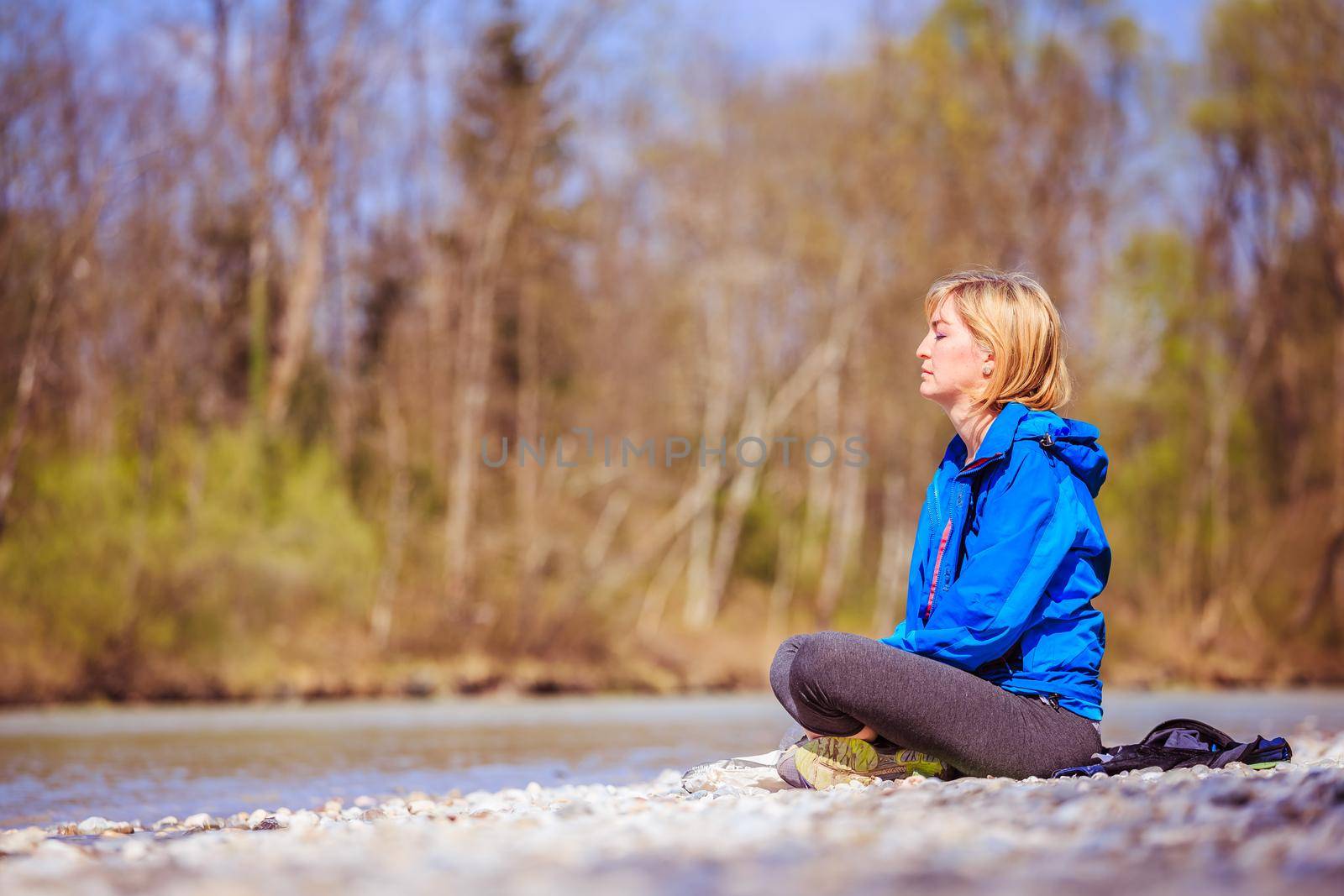 Woman is sitting on a pebble beach and doing meditation