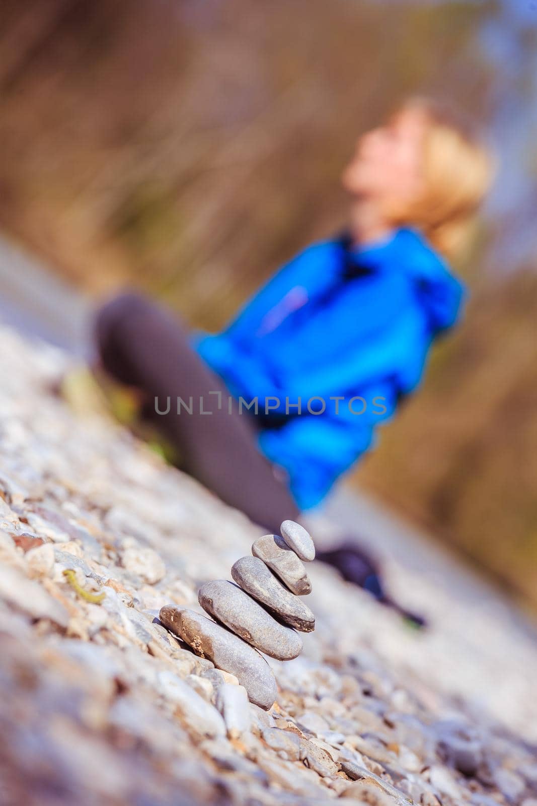 Cairn on a pebble beach, meditating woman in the background