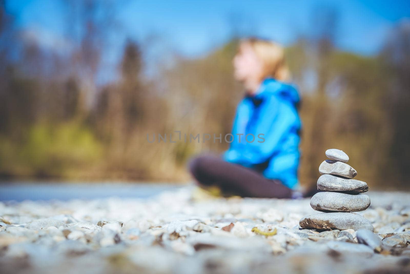 Cairn on a pebble beach, meditating woman in the background