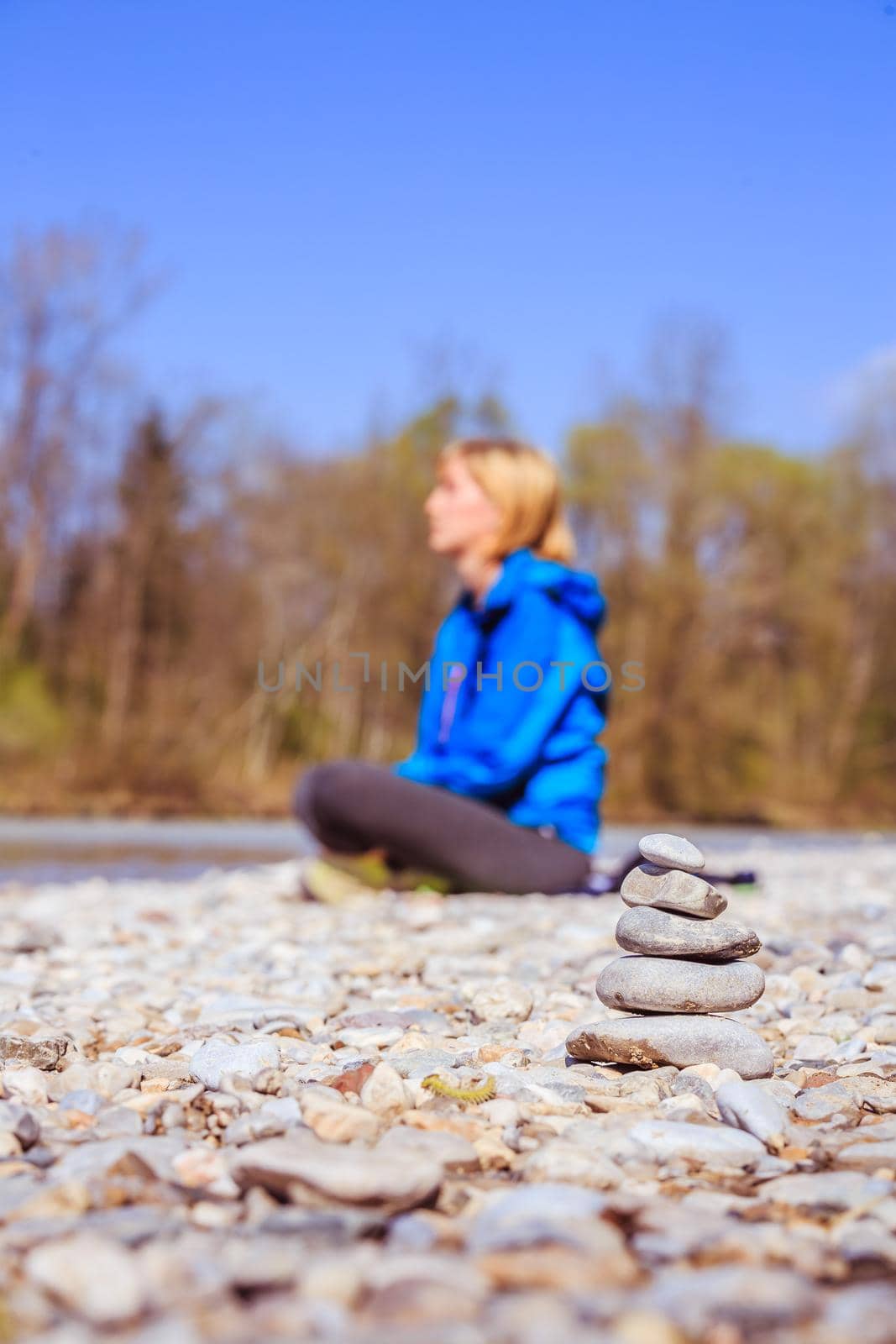 Cairn on a pebble beach, meditating woman in the background