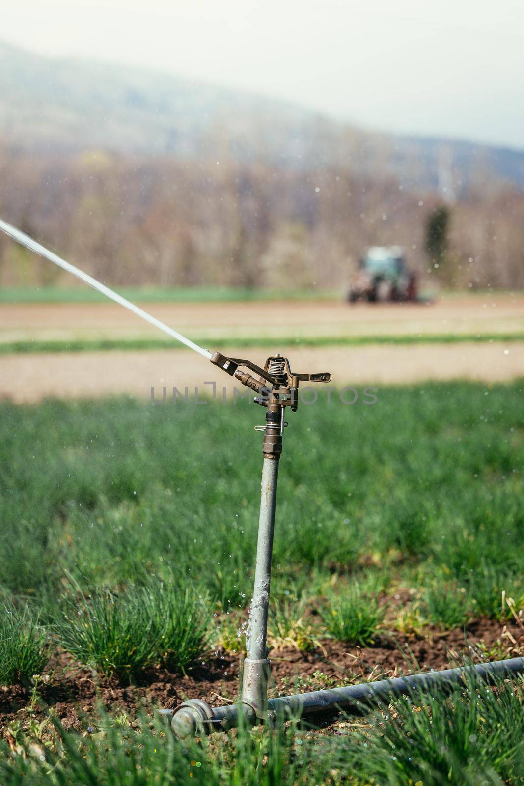 Irrigation plant on an agriculture field, tractor in the background.