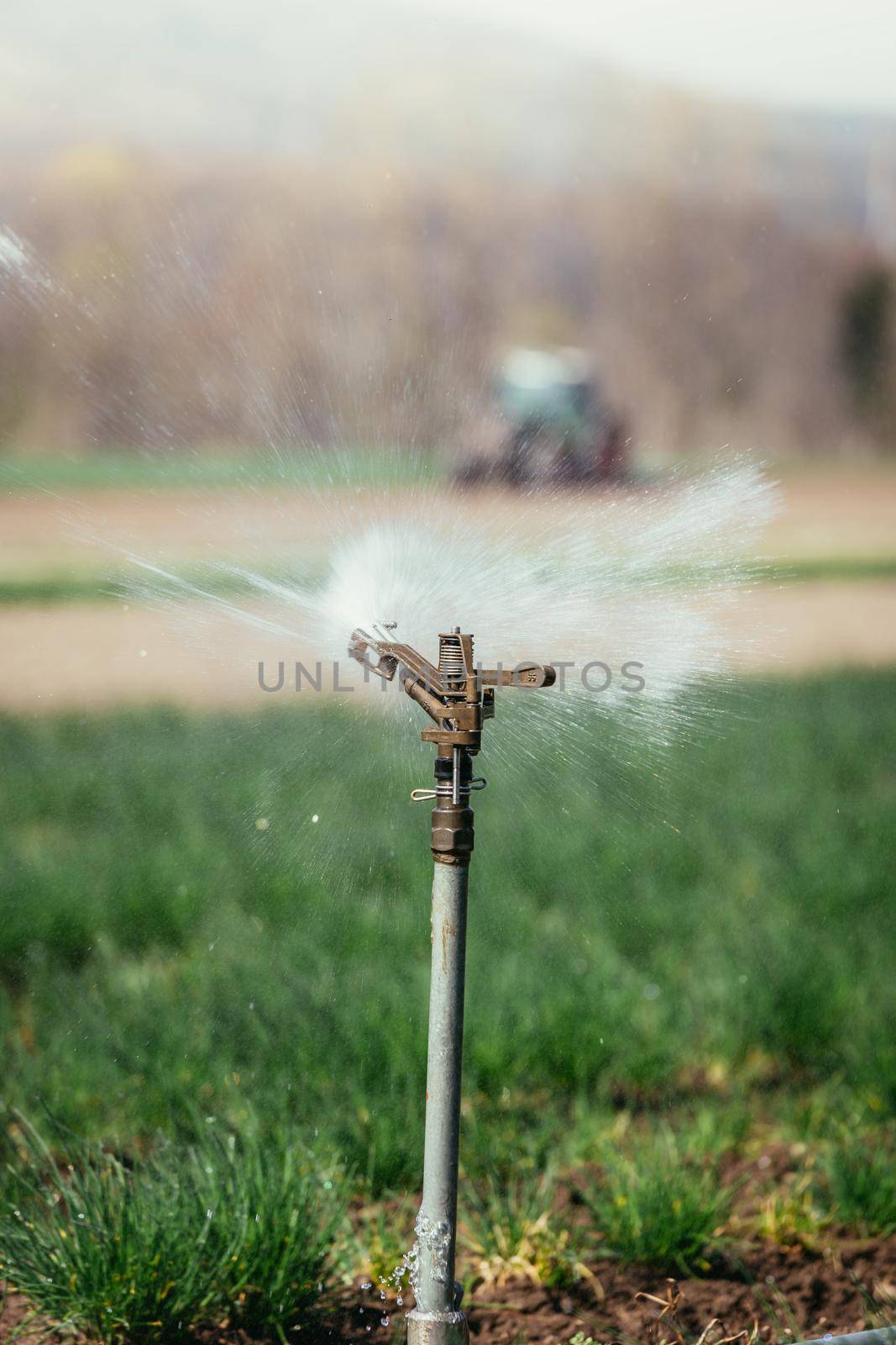 Irrigation plant on an agriculture field, tractor in the background.