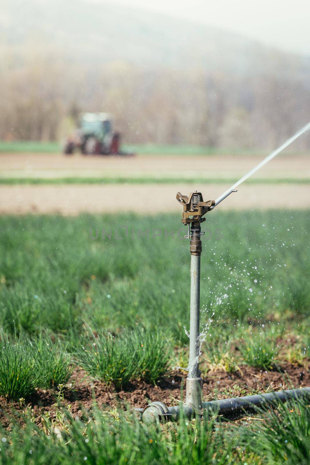 Irrigation plant on an agriculture field, tractor in the background.