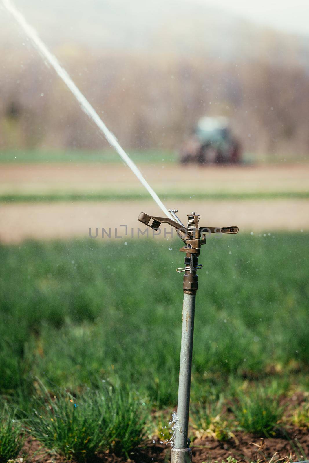 Irrigation plant on an agriculture field, tractor in the background.