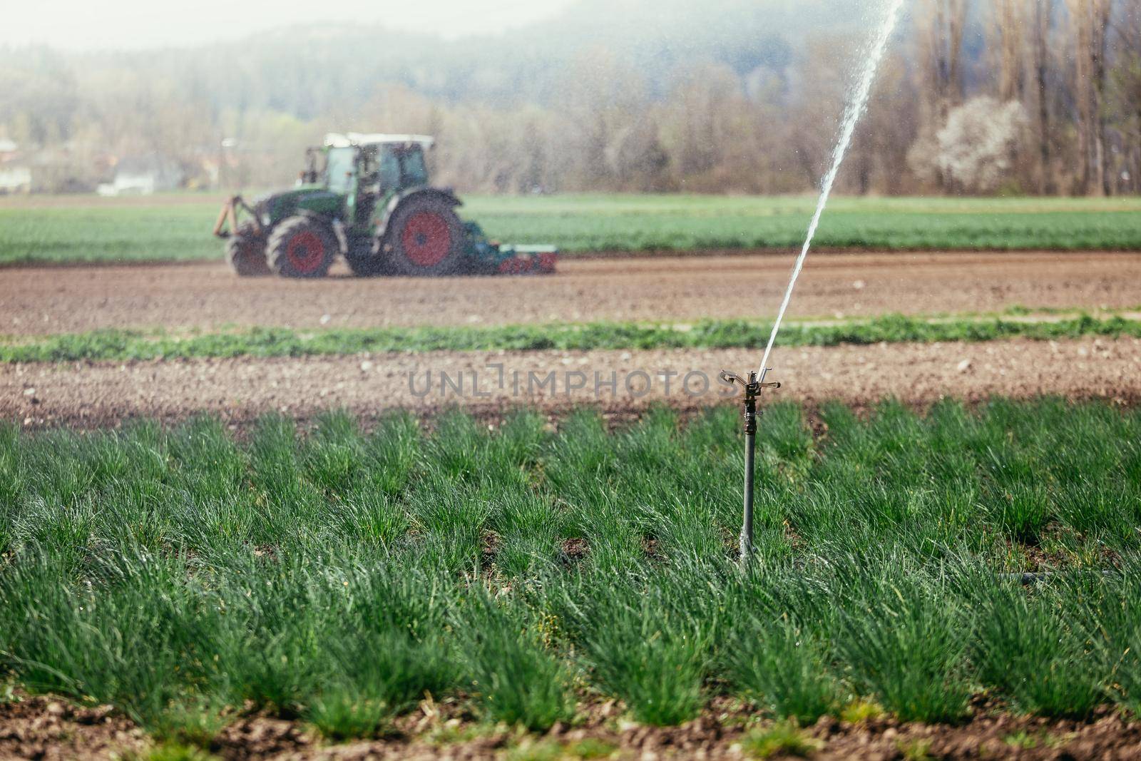 Irrigation plant on an agriculture field, tractor in the background.