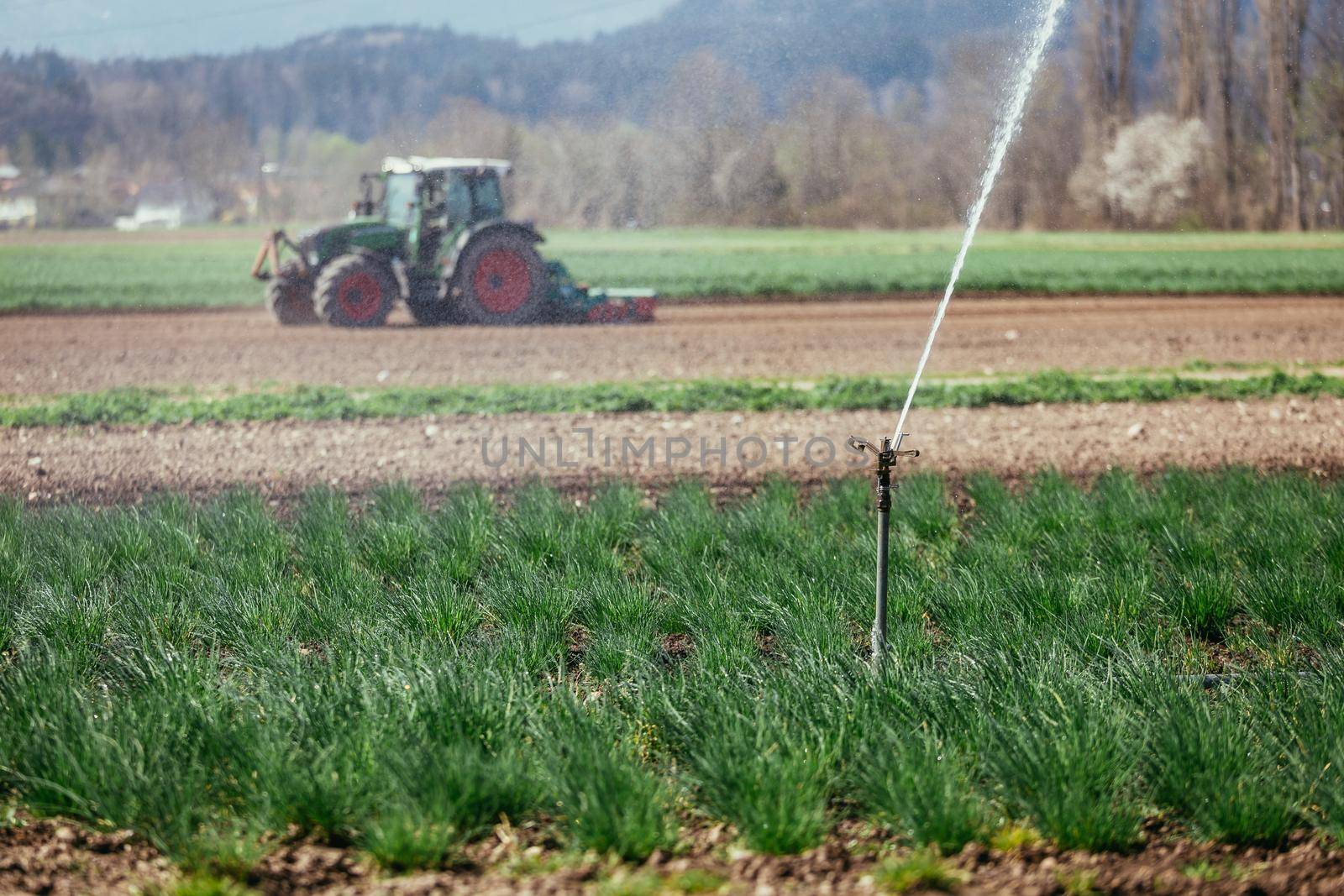 Irrigation plant on an agriculture field, tractor in the background.