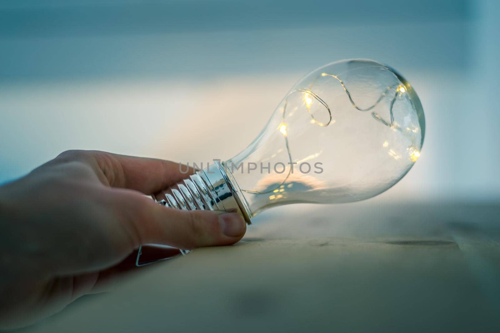 Hands are holding a LED lightbulb over the wooden floor. Symbol for ideas and innovation. Window