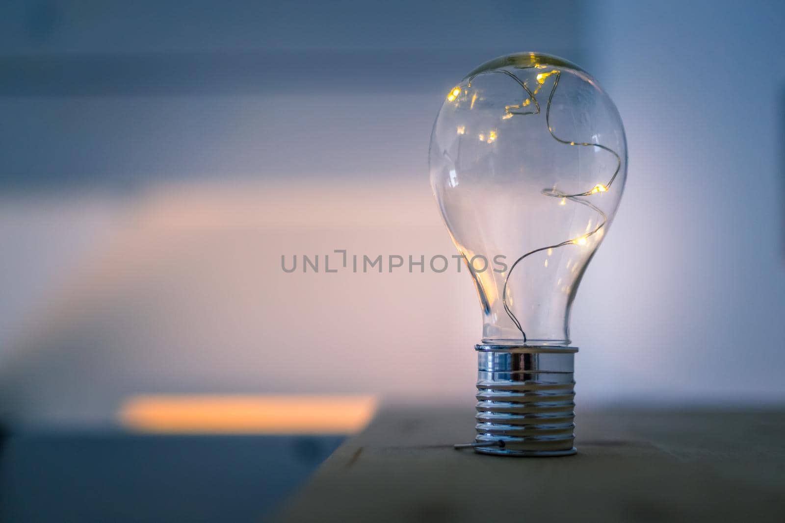 LED light bulb is lying on a wooden table. Symbol for ideas and innovation. Spot lights in the blurry background.