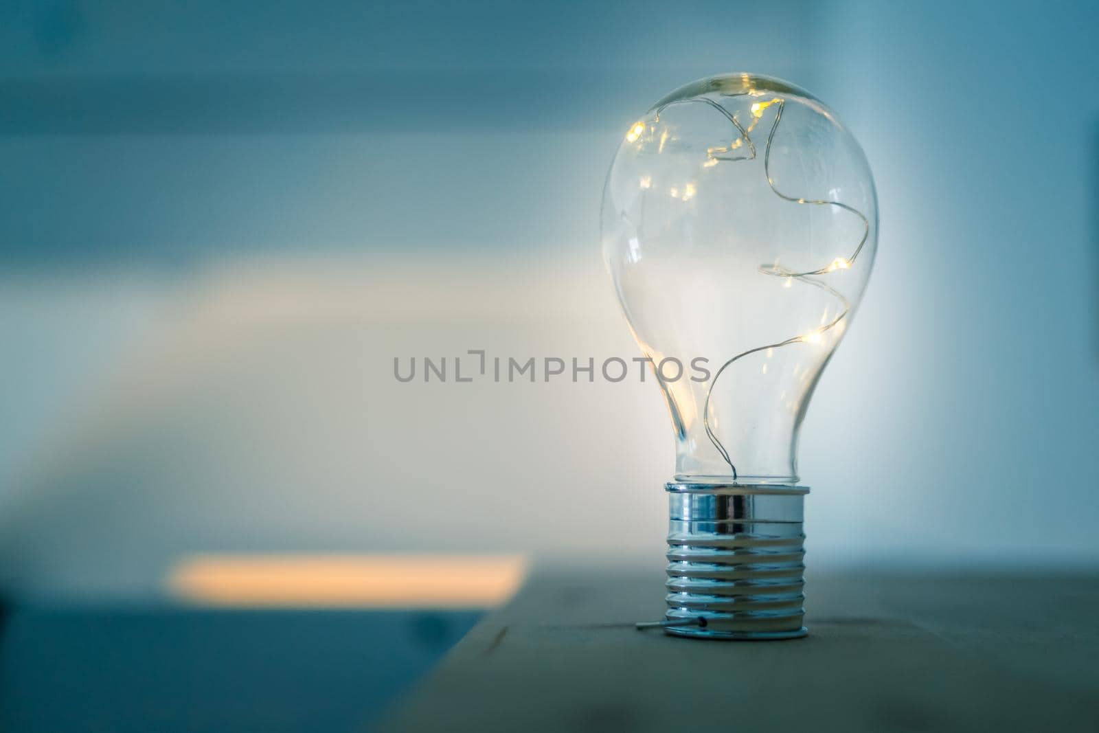 LED light bulb is lying on a wooden table. Symbol for ideas and innovation. Spot lights in the blurry background.