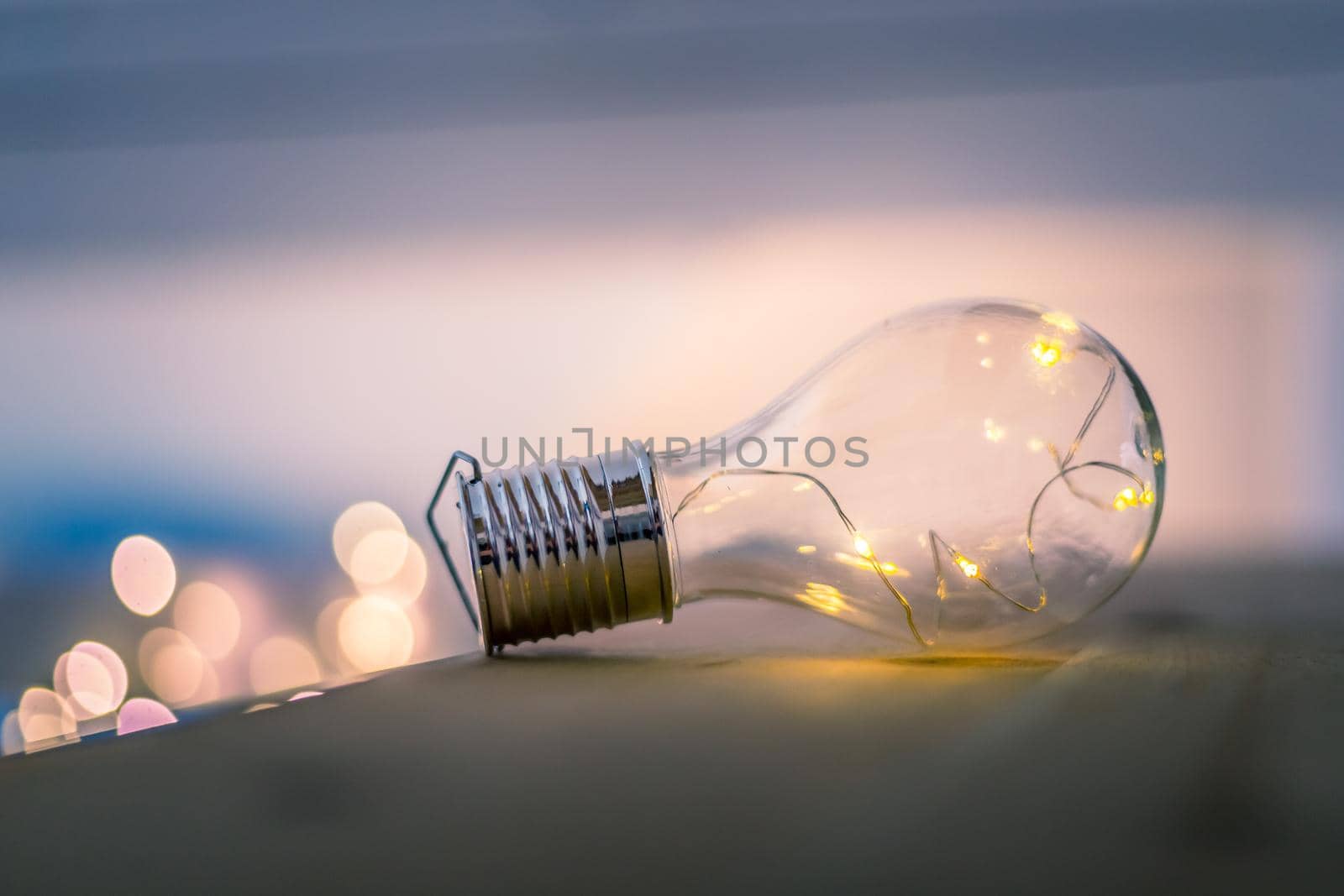 LED light bulb is lying on a wooden table. Symbol for ideas and innovation. Spot lights in the blurry background.