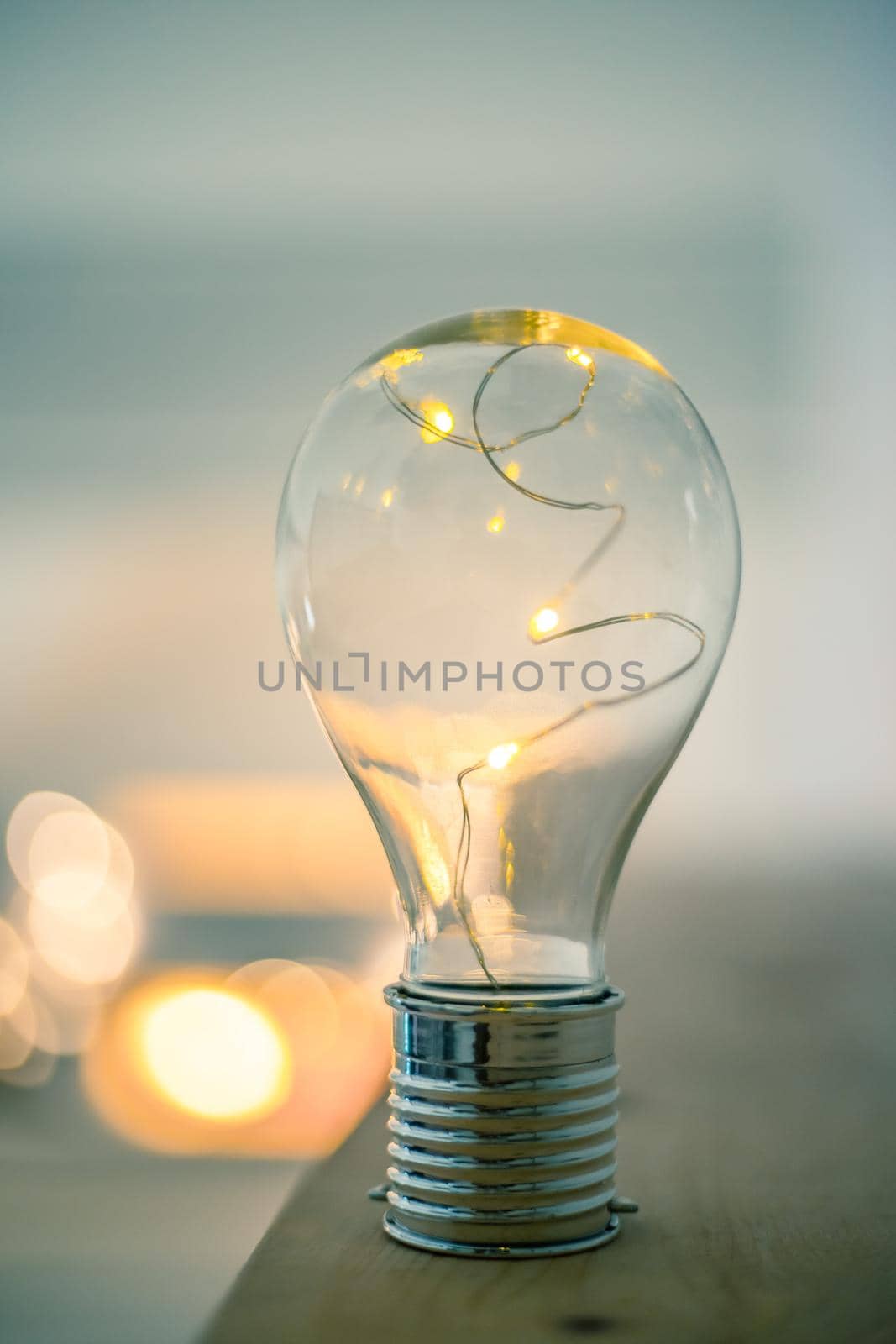 LED light bulb is lying on a wooden table. Symbol for ideas and innovation. Spot lights in the blurry background.