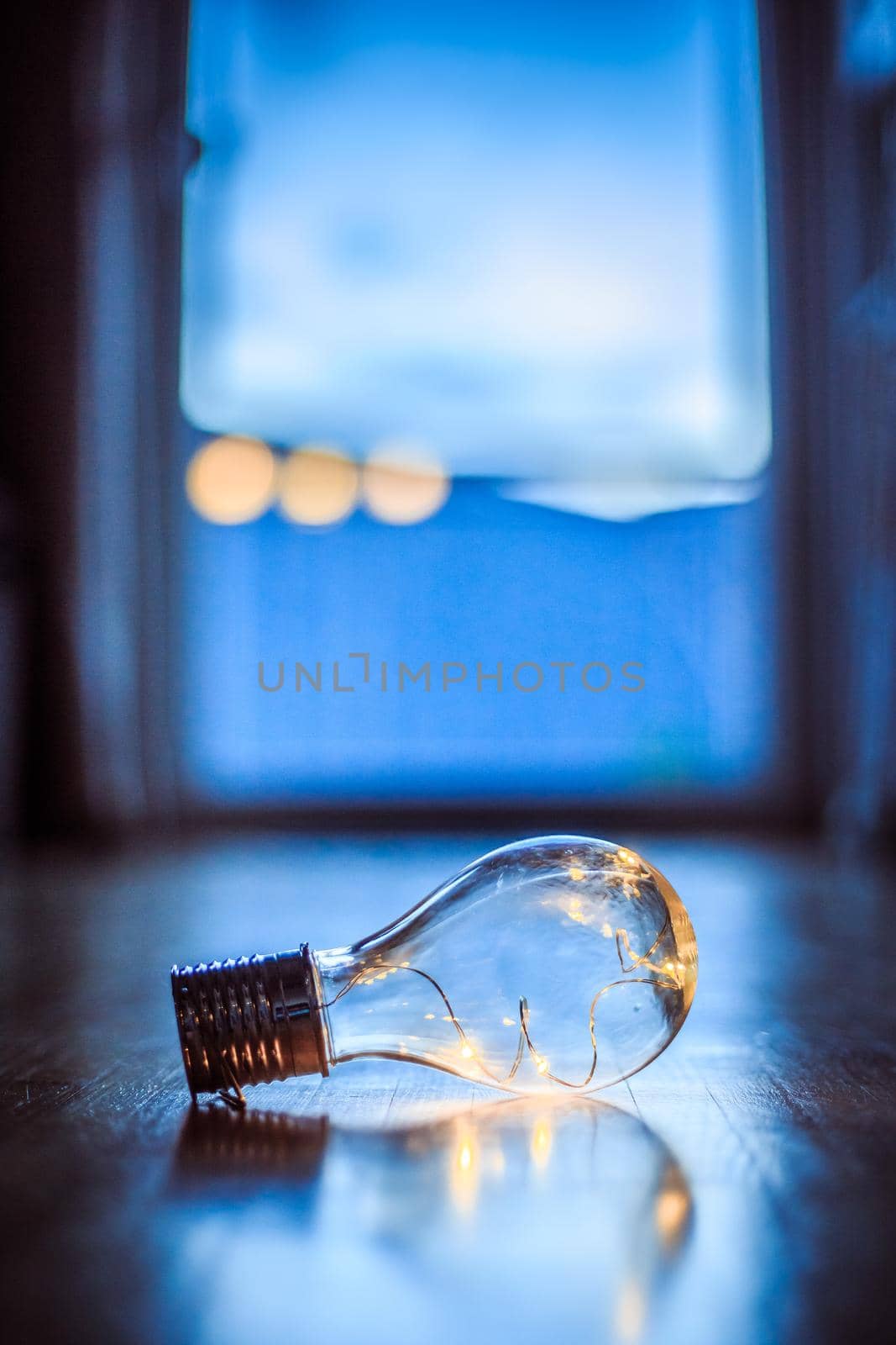 LED light bulb is lying on the wooden floor. Symbol for ideas and innovation. Window and light in the blurry background.