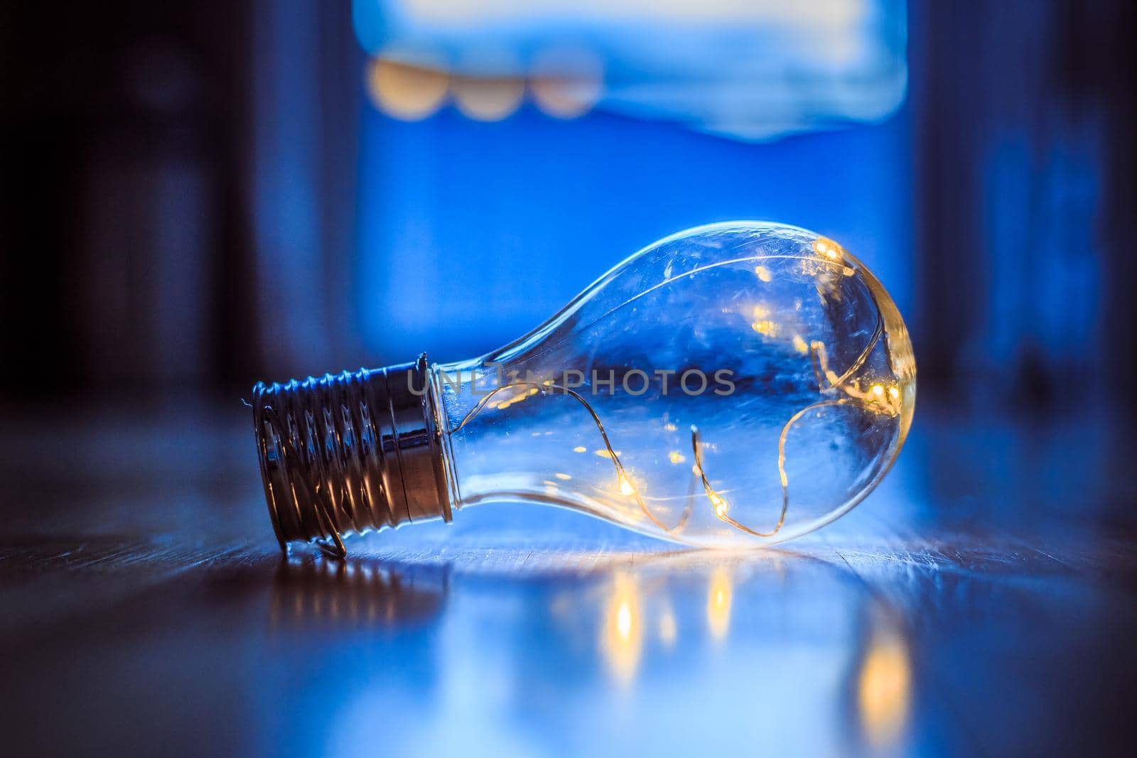 LED light bulb is lying on the wooden floor. Symbol for ideas and innovation. Window and light in the blurry background.