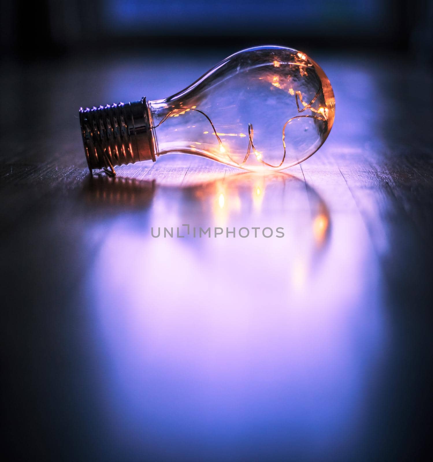 LED light bulb is lying on the wooden floor. Symbol for ideas and innovation. Window and light in the blurry background.