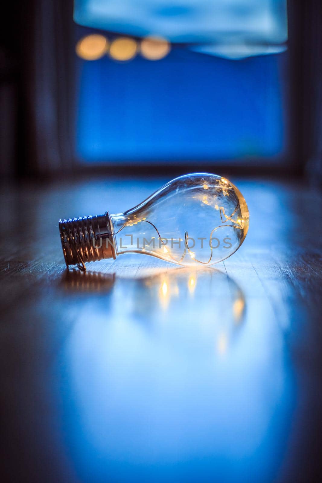 Ideas and innovation: Light bulb with LEDs is lying on the wooden floor. Window and light in the blurry background. by Daxenbichler