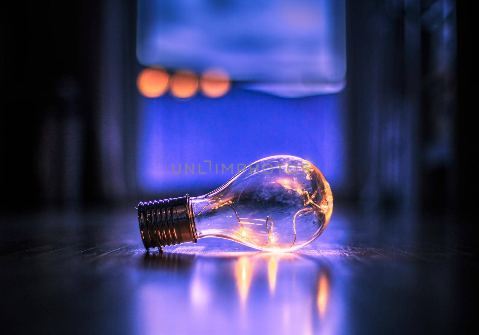LED light bulb is lying on the wooden floor. Symbol for ideas and innovation. Window and light in the blurry background.