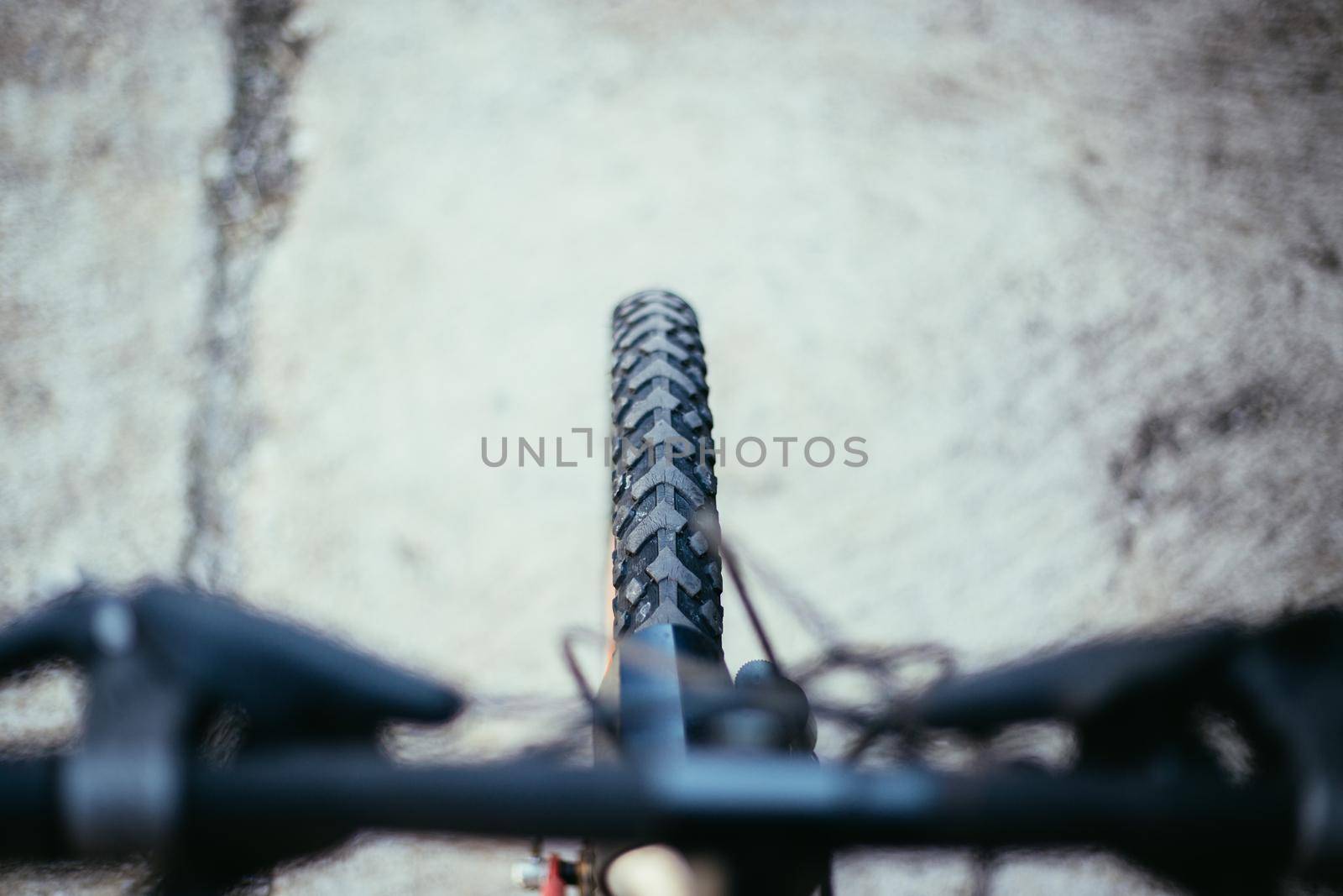 Close up picture of a mountain bike tyre, blurry handlebar, summer day