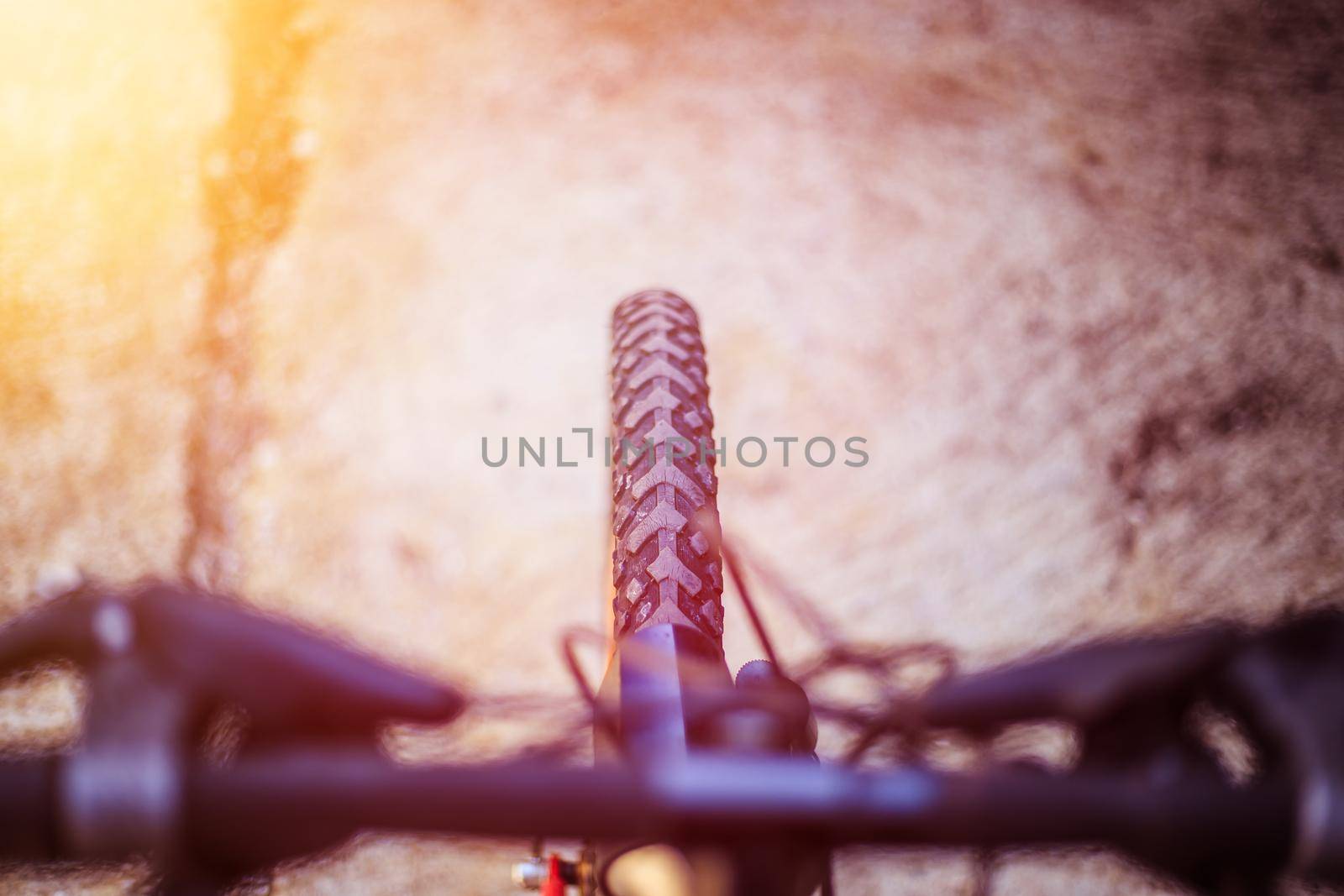 Close up picture of a mountain bike tyre, blurry handlebar, summer day