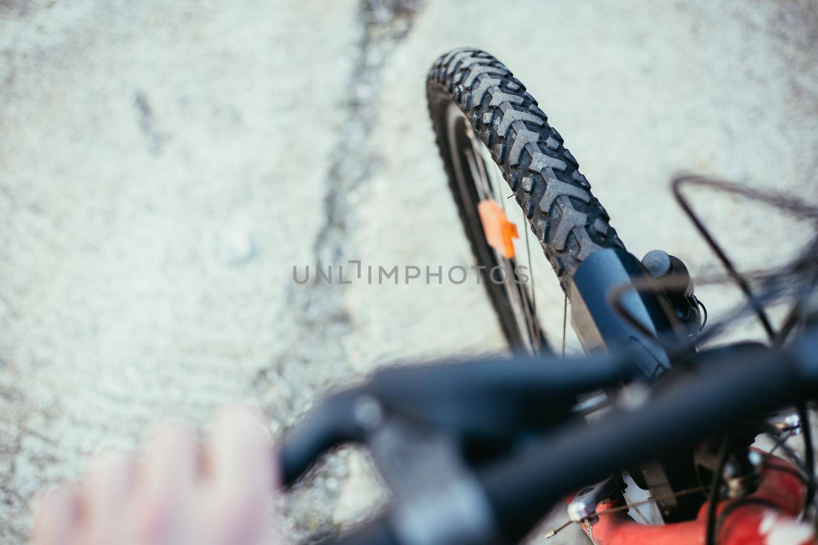 Close up picture of a mountain bike tyre, blurry handlebar, summer day