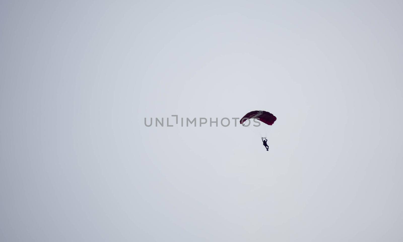 silhouette parachute stunt unfocused and blurry while gliding in the air with blue sky