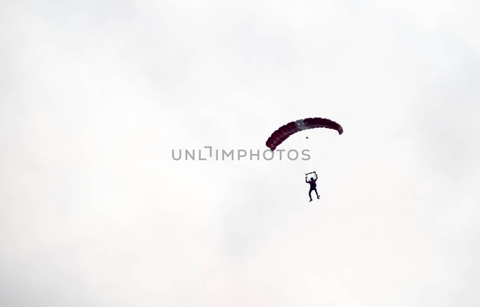 silhouette parachute stunt unfocused and blurry while gliding in the air with blue sky