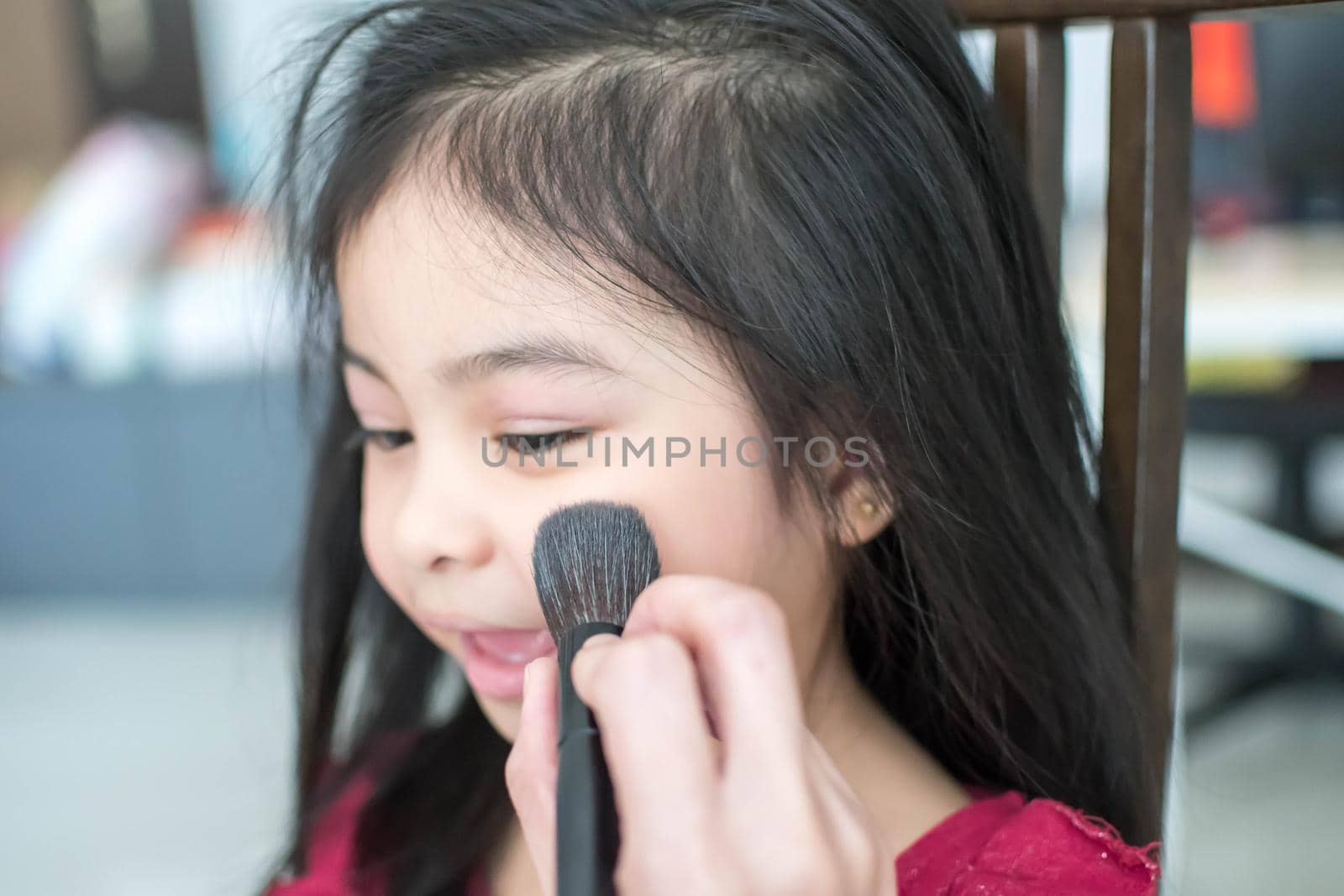 Pretty cute little girl while having a makeup, lipstick and blush on