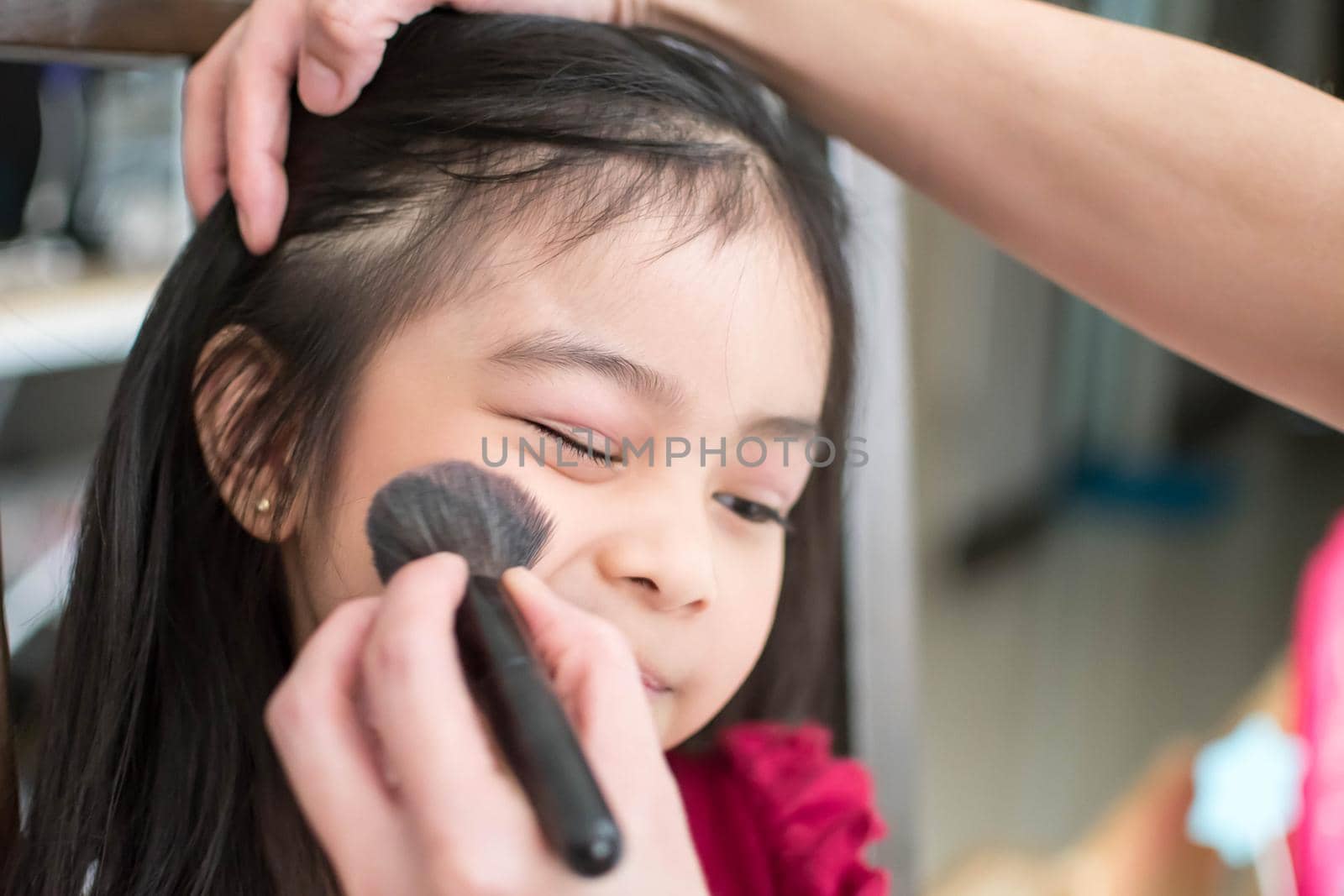 Pretty cute little girl while having a makeup, lipstick and blush on