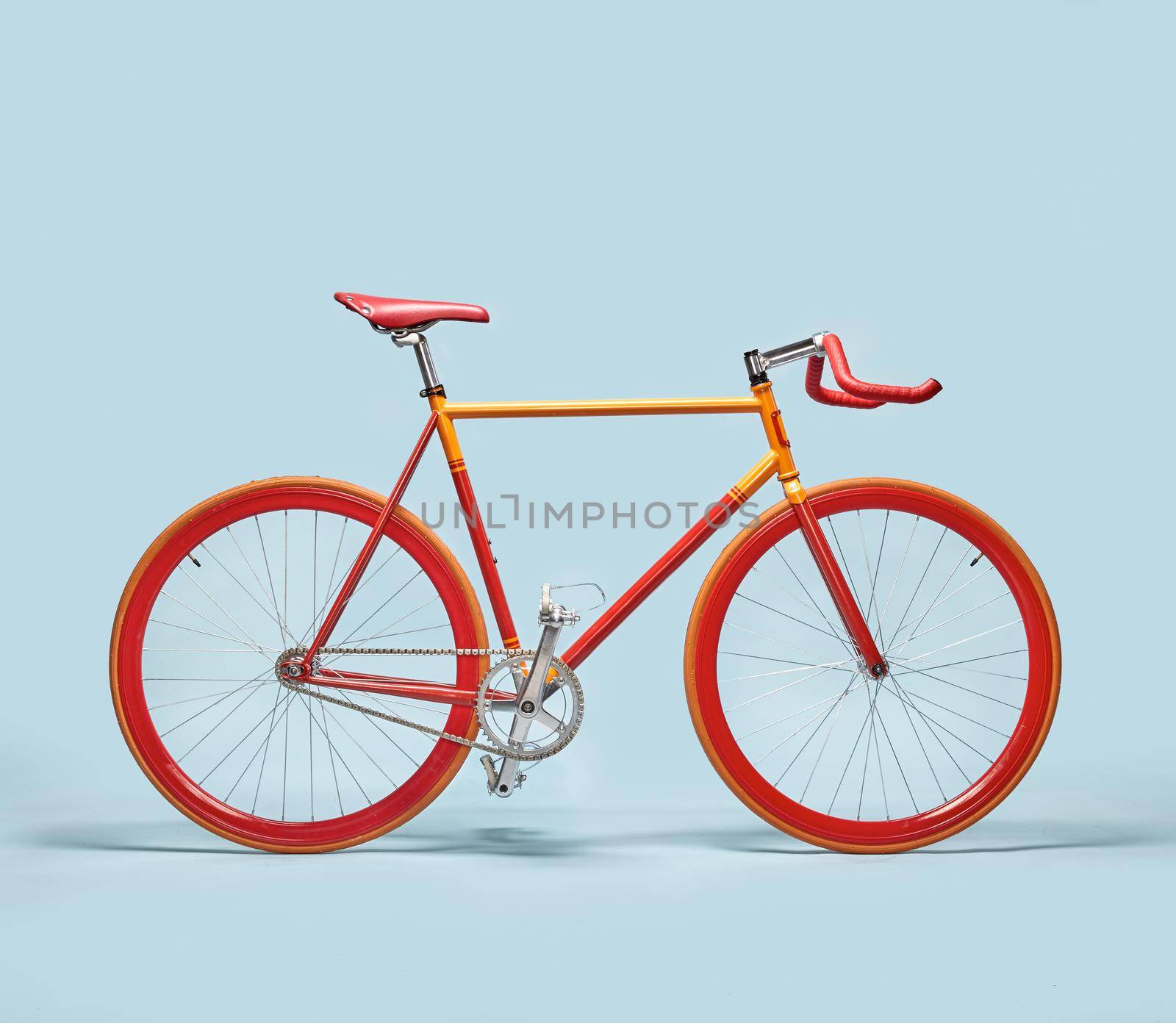 Trendy orange and red bicycle isolated on a blue background