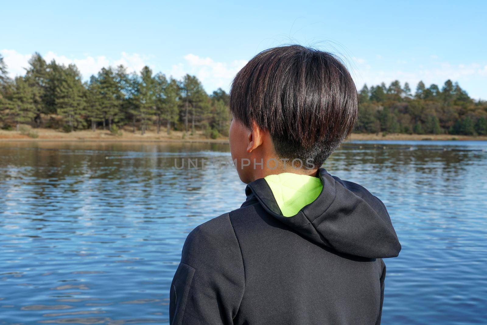 Young sporty Asian boy looking at the view by the Lake. Teenager concept