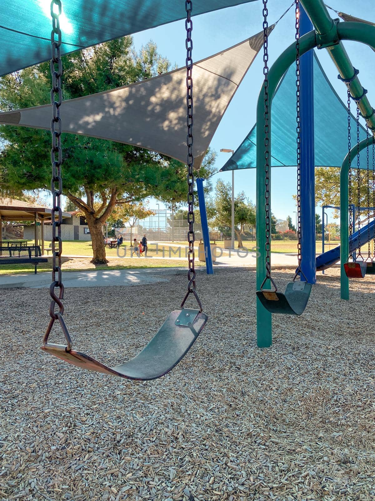 Swing at children playground activities in public park. Slide, swing on modern playground. Urban neighborhood childhood concept. 
