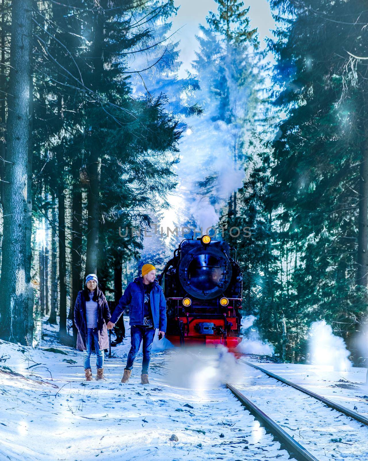 couple men and woman hiking in the Harz national park Germany, Steam train on the way to Brocken through the winter landscape, Famous steam train through the winter mountain. Brocken, Harz Germany