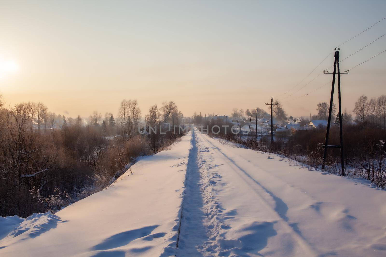 A snow-covered railway and a path trodden by people on it in winter. by AnatoliiFoto