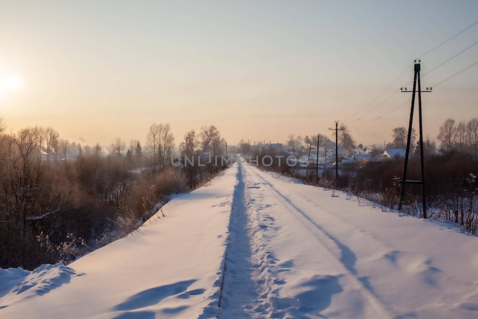 A snow-covered railway and a path trodden by people on it in winter. Lots of snow. Iron rails a track for a train in the direction of cargo covered with snow at a railway crossing in winter