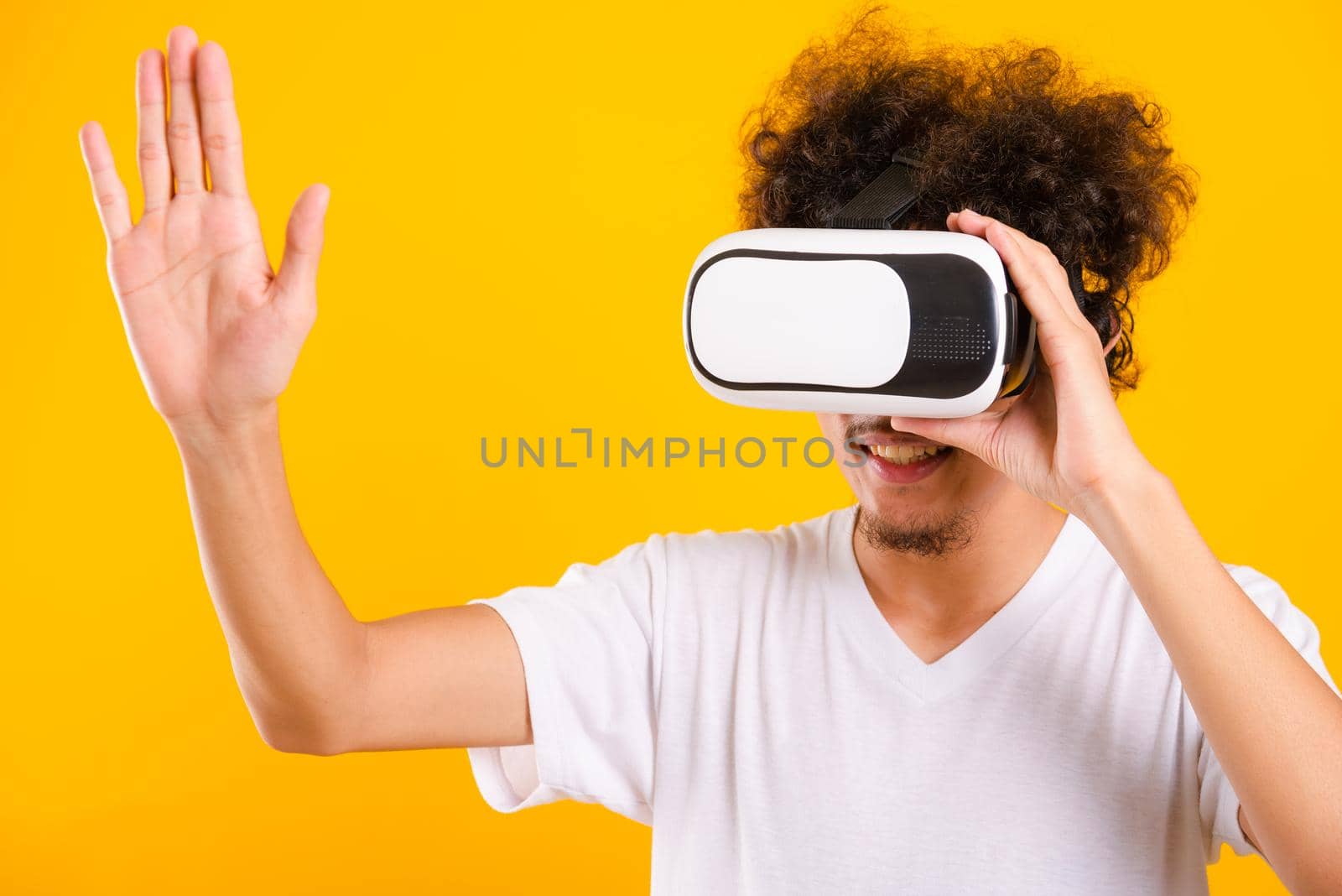 Asian handsome man with curly hair he using virtual reality headset or VR glass by Sorapop