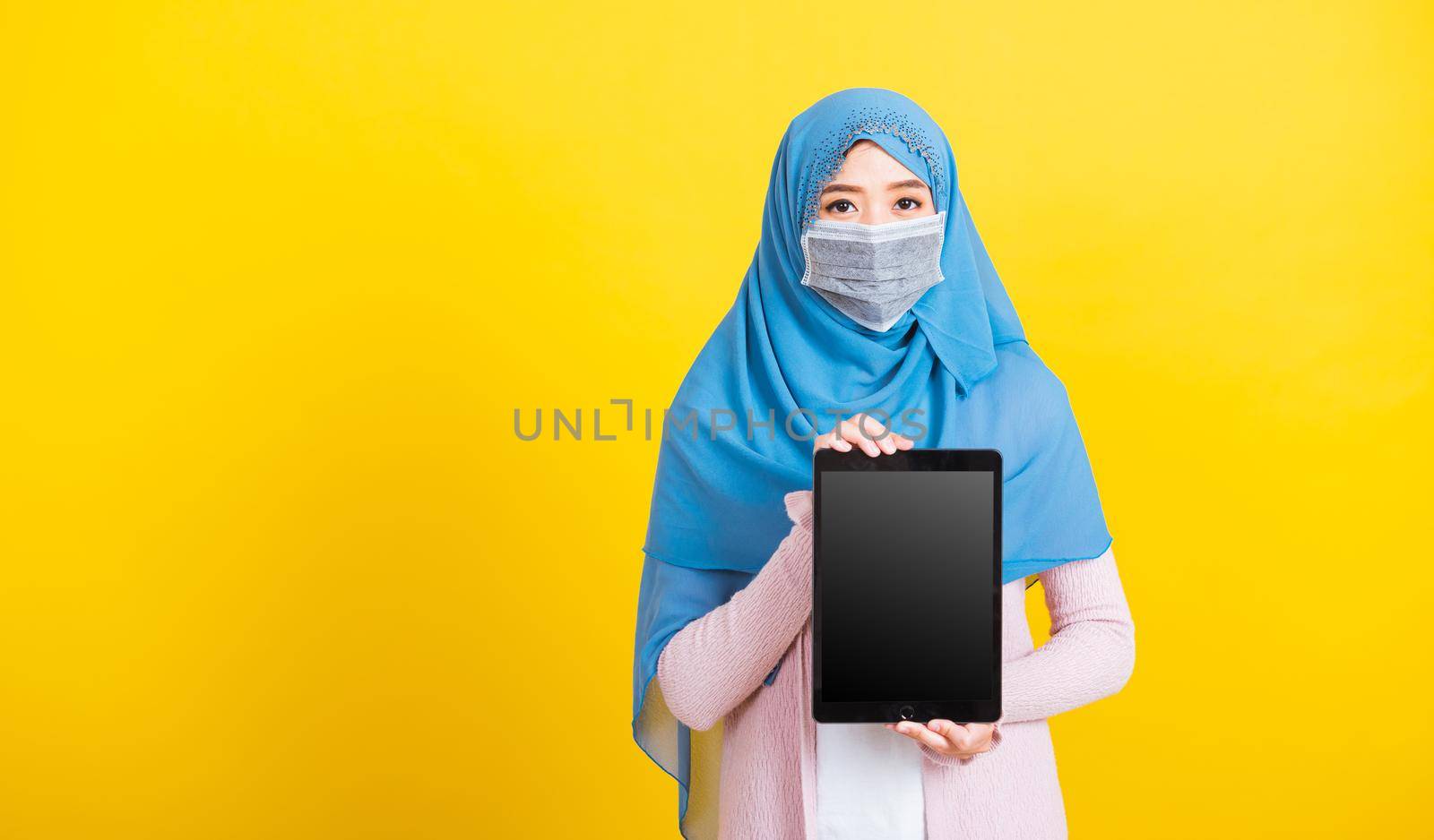 Asian Muslim Arab woman Islam religious wear veil hijab and face mask show blank screen tablet by Sorapop