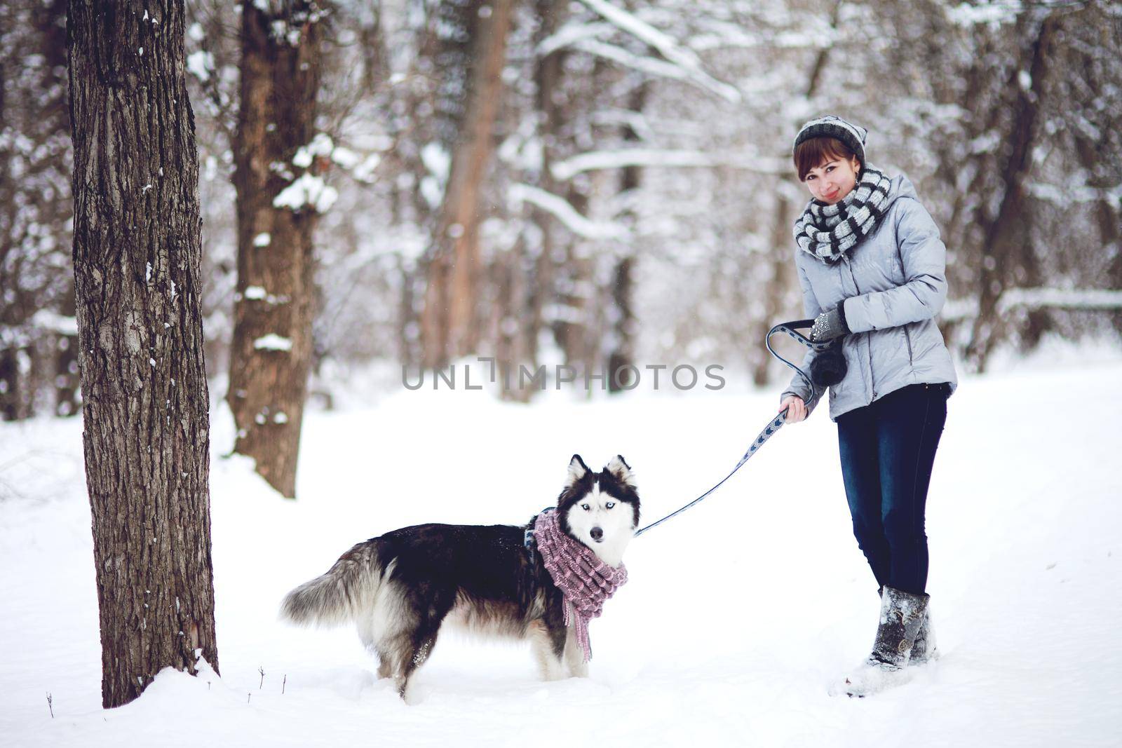 Girl walks with dog siberian husky in winter snowy forest by selinsmo