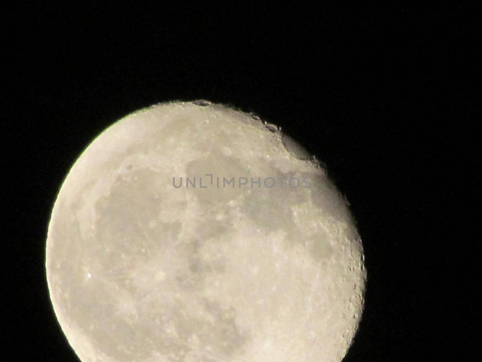 Earth's Moon Glowing On Black Background. The Moon close-up on a black night sky shot through a telephoto camera.