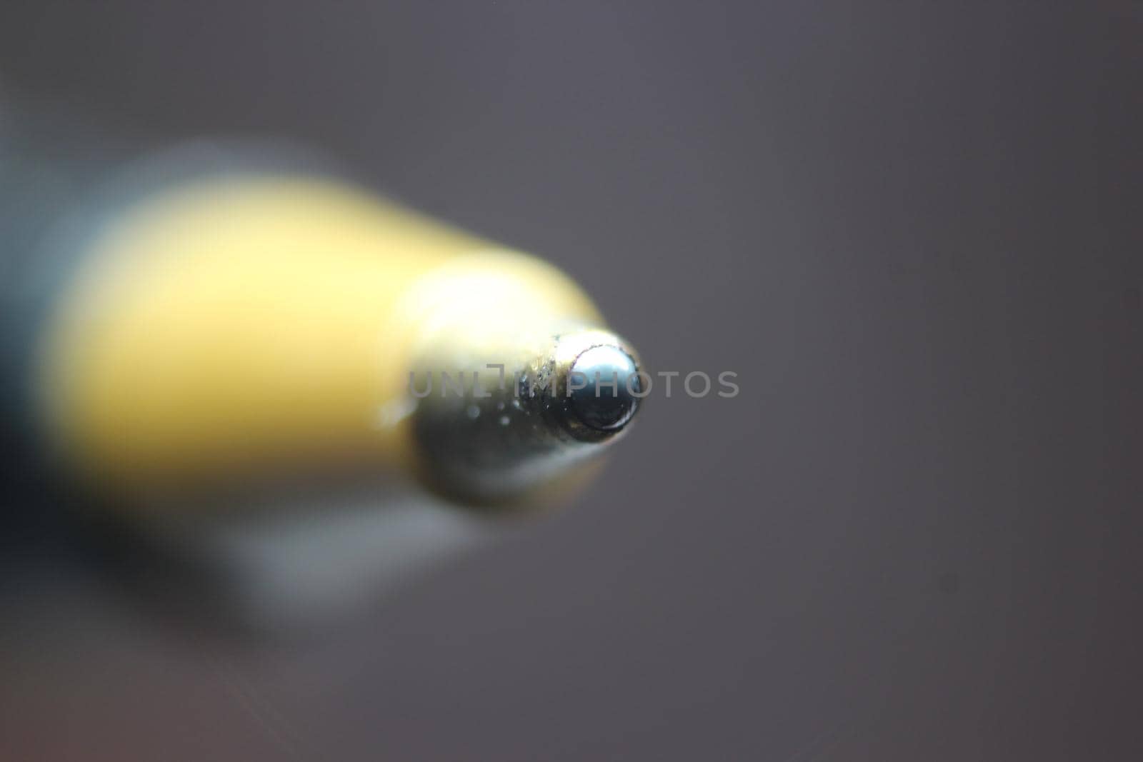 Macro photo of ballpoint pen tip with dark grey background. by Photochowk