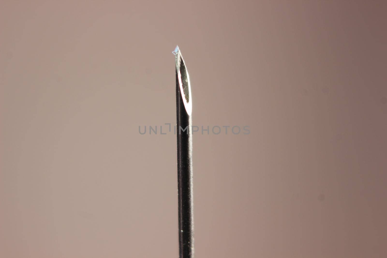 Water drop falling from the syringe needle against grey background by Photochowk