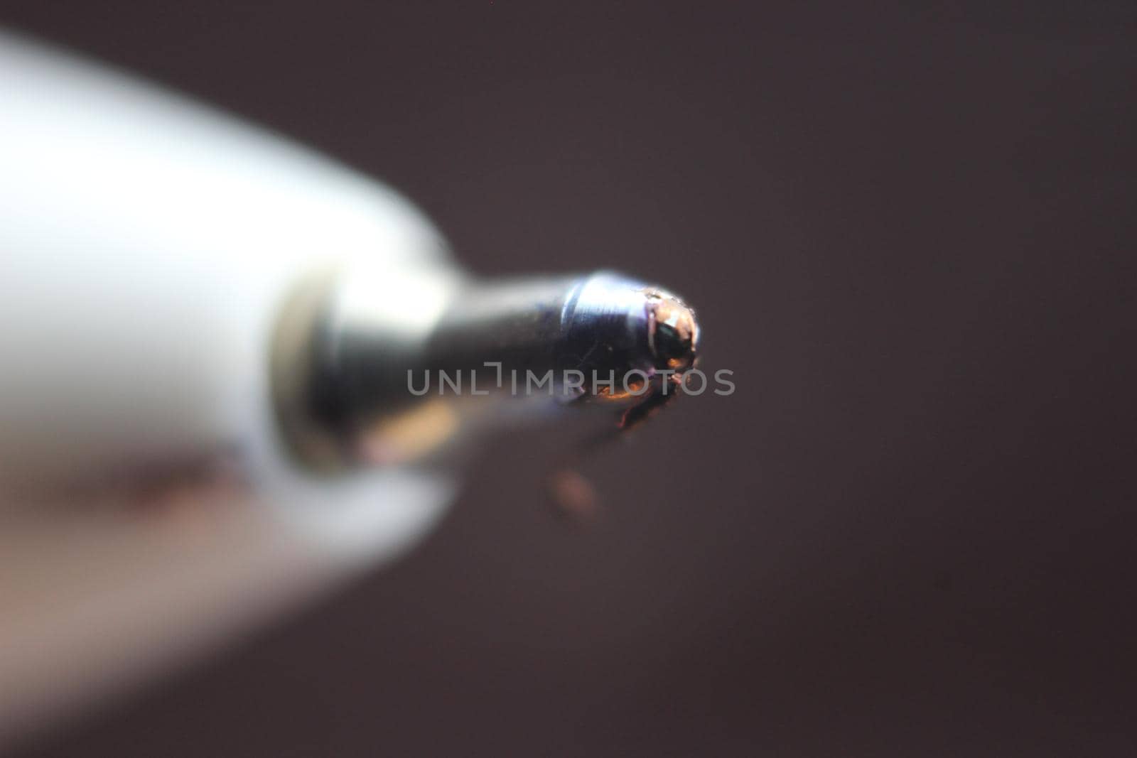 Macro photo of ballpoint pen tip with dark grey background. Extreme macro image of metal ballpoint pen on grey background.