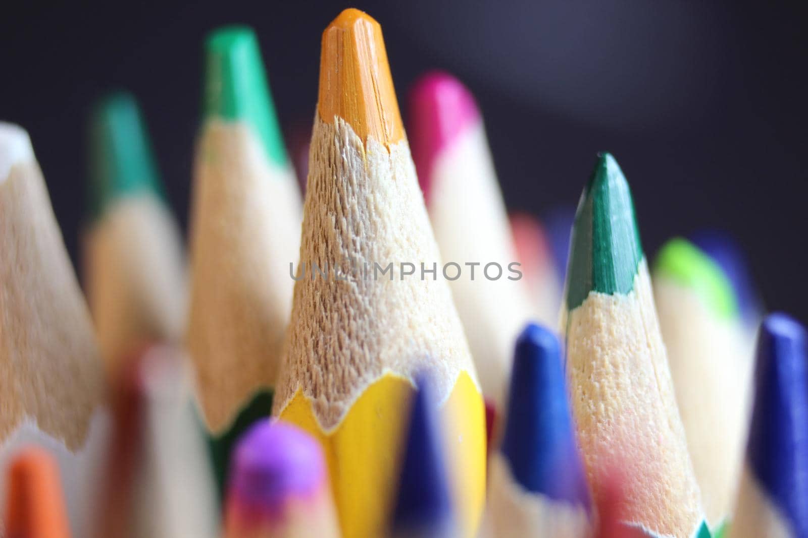 Close-up view of bright colored multicolor pencils on black background