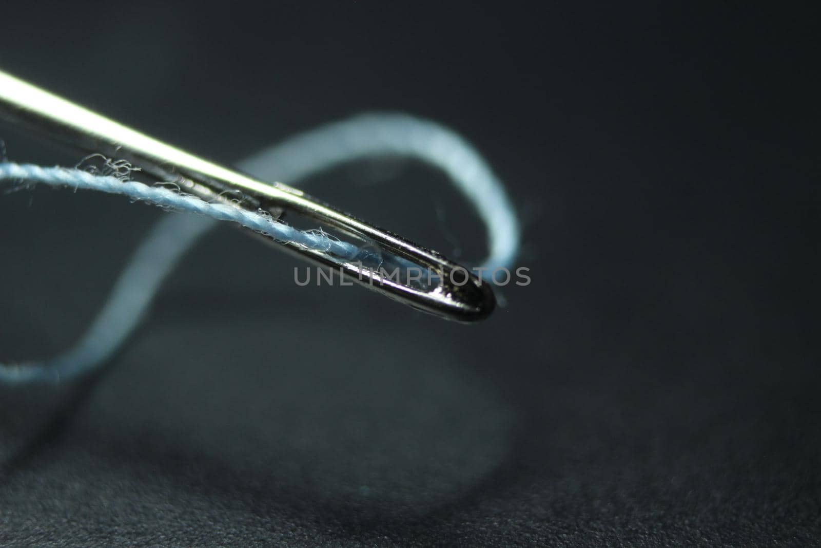 Small needle with thread in the eyelet, isolated over the black background. by Photochowk