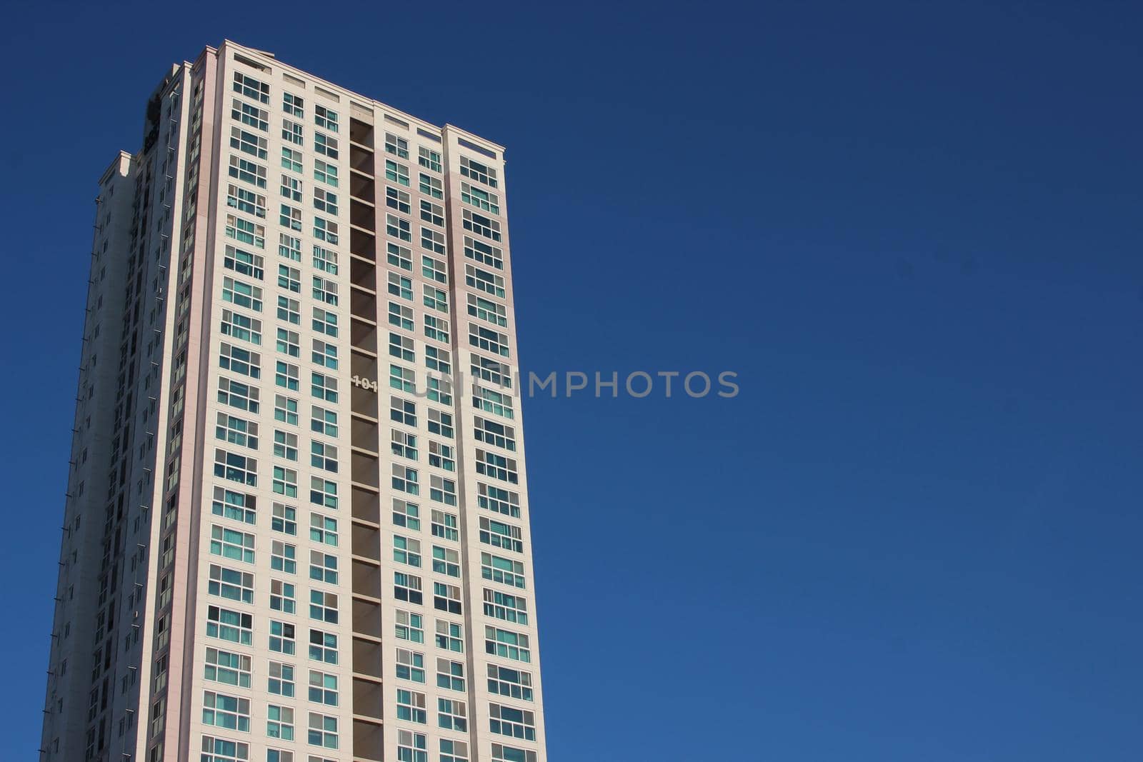 The wide-angle view of a skyscraper commercial building with blue sky on sunny day.